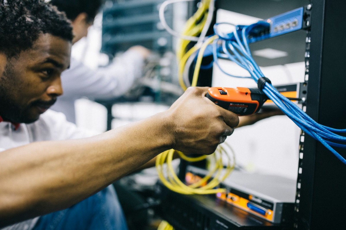 Engineer securing equipment and cabling in a network rack